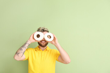 Funny young man with toilet paper on color background