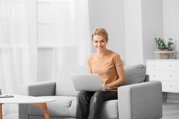 Fototapeta premium Young woman using laptop in living room