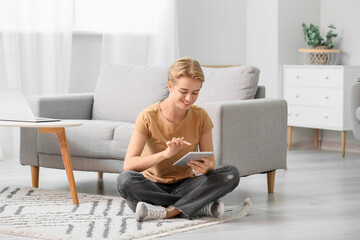 Pretty young woman using tablet computer at home
