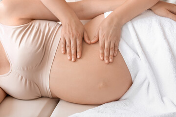 Fototapeta na wymiar Young pregnant woman having massage in spa salon
