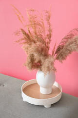 Vase with dry reeds near color wall in room