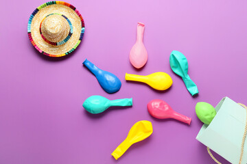 Empty party balloons and sombrero on color background