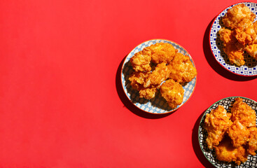 Plates with popcorn chicken on color background