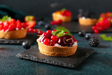 Board with tasty berry tart on table
