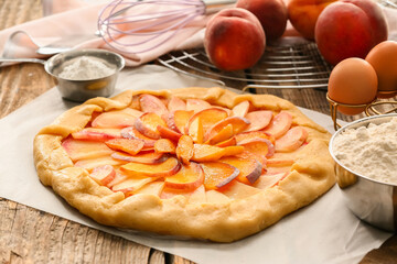 Parchment with raw peach galette on wooden background, closeup