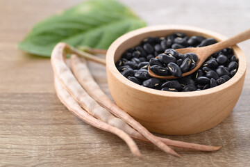 Black kidney beans in a bowl with spoon on wooden background