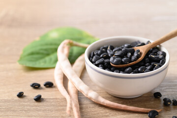 Black kidney beans in a bowl with spoon on wooden background