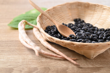 Black kidney beans in a bamboo basket with spoon on wooden background
