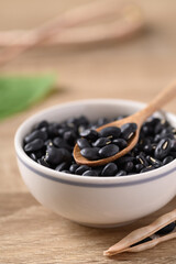 Fototapeta na wymiar Black kidney beans in a bowl with spoon on wooden background