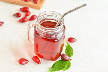 Mason jar of healthy dogwood berry drink on light background