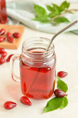 Mason jar of healthy dogwood berry drink on light background