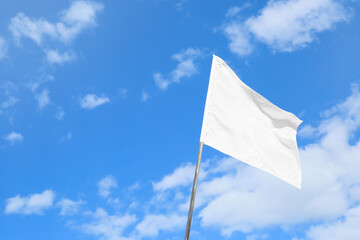 Waving white flag against blue sky