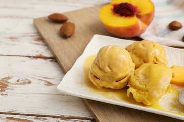 Plate of tasty peach ice cream on white wooden background