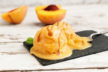 Board of tasty peach ice cream on white wooden background