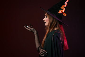 Young witch on dark background