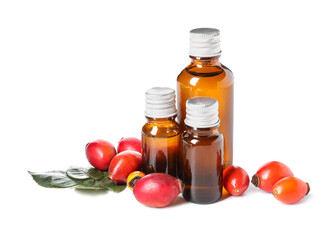 Bottles of essential oil and ripe rose hip berries isolated on white background