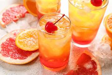 Glasses of tasty Tequila Sunrise cocktail with fresh fruits on white background