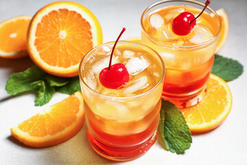 Glasses of tasty Tequila Sunrise cocktail and fresh orange slices on white background