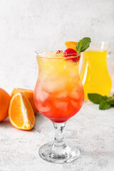 Glass of cold Tequila Sunrise cocktail on light background