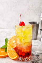 Glass of cold Tequila Sunrise cocktail on light background