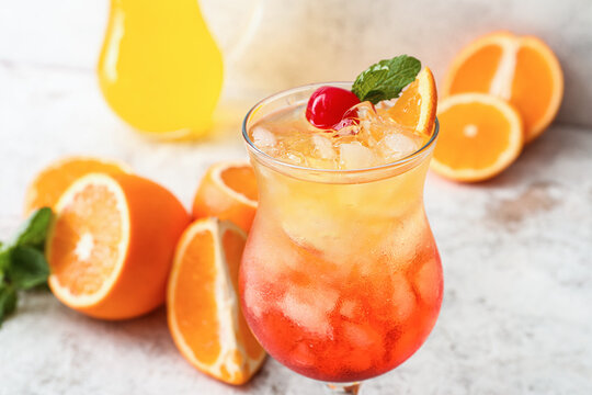 Glass of tasty Tequila Sunrise cocktail on light background, closeup