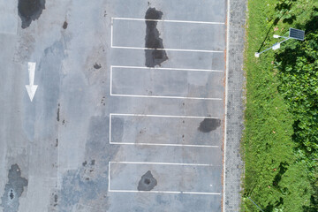 Aerial view top down of empty car parking lot with white line of traffic sign on the street. Above...