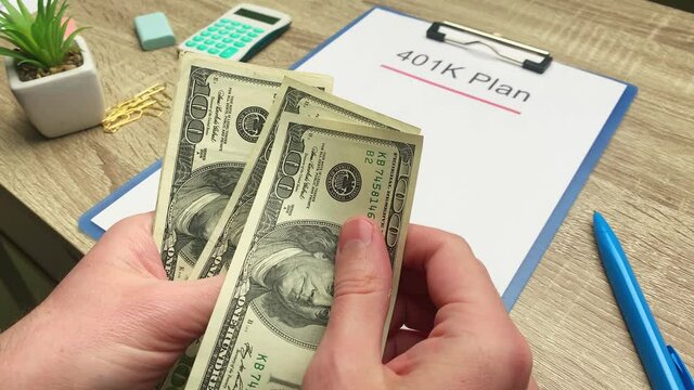 401k retirement plan, a man counts 100 dollar bills at a wooden table