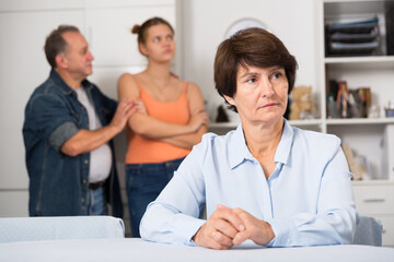 Adult woman is upseting and her husband with daughter are sympathying with her at home.