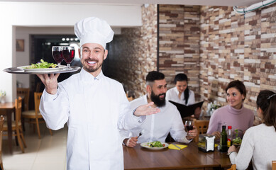 Positive male cook welcoming visitors to country restaurant