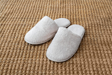 Fototapeta na wymiar White indoor slippers on jute rug