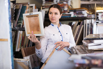 Young woman is standing with modern pictures in furniture store