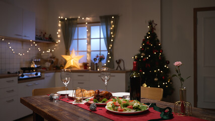 romantic table setting dinner for two in a decorated home interior with christmas tree and led lights
