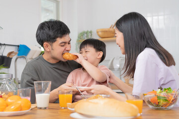 Happy refreshment family breakfast in morning, asian young parent father, mother and little cute boy, child having meal in kitchen eating together at home. Cheerful, enjoy cooking people.