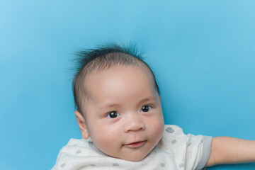 Asian baby boy lying on light blue with a copy space