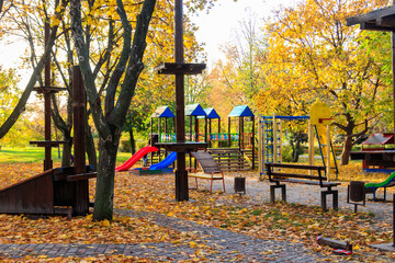 Colorful playground equipment for children in public park at autumn