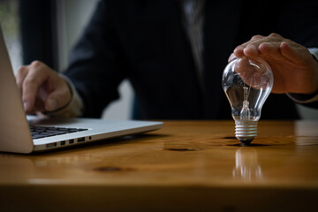 businessman holding a light bulb with a laptop, financial instruments New ideas for business and...