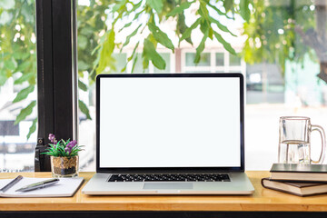 blank white screen laptop and computer screen Flower vases of plants and book objects on the table in a coffee shop front view beside the mirror