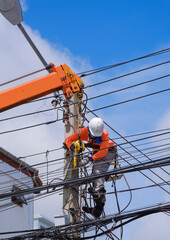 Asian electrician with crane truck is installing cable lines and electrical transmission on...