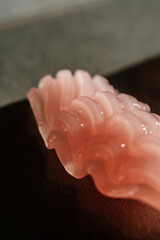 The texture of a pink cosmetic butter on a gray background.