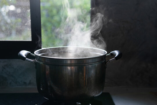 Steaming pot on black background. Smoke above boiling soup pot.,hot food and healthy meal concept
