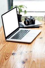 Mockup blank white screen laptop computer on wooden table.