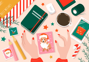 vector flat illustration on the theme of preparation for christmas, gift wrapping and postcards. female hands hold a postcard, on the table there is wrapping paper, threads, coffee, a notebook.