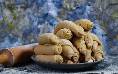Closeup of raw peruvian churros, traditional Peruvian dessert before frying on a plate with an artistic light blue background