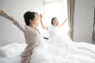Obraz premium 部屋の中で逆光の朝日を浴びてストレッチをする日本人の夫婦2