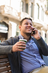 Man walking on the street, drinking coffee, talking by phone