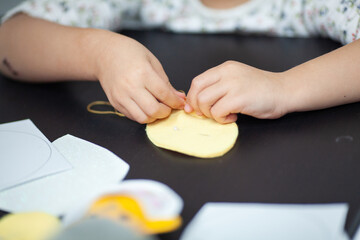 A little girl sews with a needle. Sewing training. Children's hands hold a thread with a needle. Children's creativity and needlework. The child sews clothes for the doll.