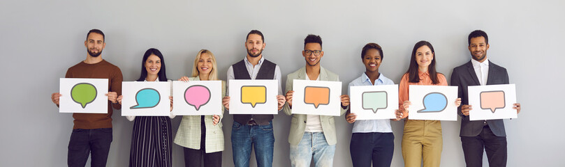 Different multiracial multiethnic people holding various cards and sheets of paper with pictures of colorful mockup chat message bubble icons. Concept of communication via messengers and social media - Powered by Adobe