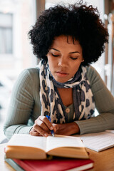 Mid adult black woman studying from books in a library.