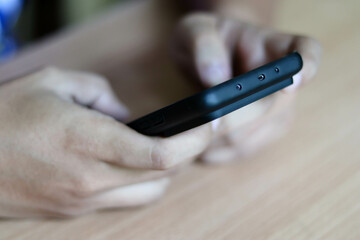 Businessman hand holding and using smartphone or laptop for SMS messages, man typing touchscreen cell phone in the office. business, lifestyle, technology and Social media network concept