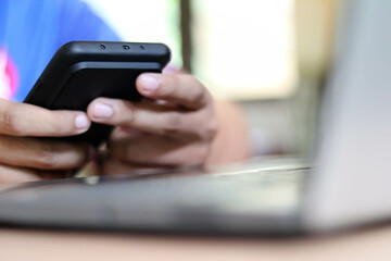 Businessman hand holding and using smartphone or laptop for SMS messages, man typing touchscreen cell phone in the office. business, lifestyle, technology and Social media network concept